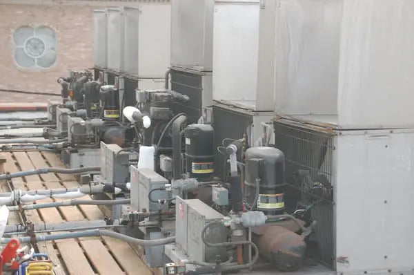 Commercial rooftop refrigeration and HVAC units with compressors and piping installed for industrial cooling systems.